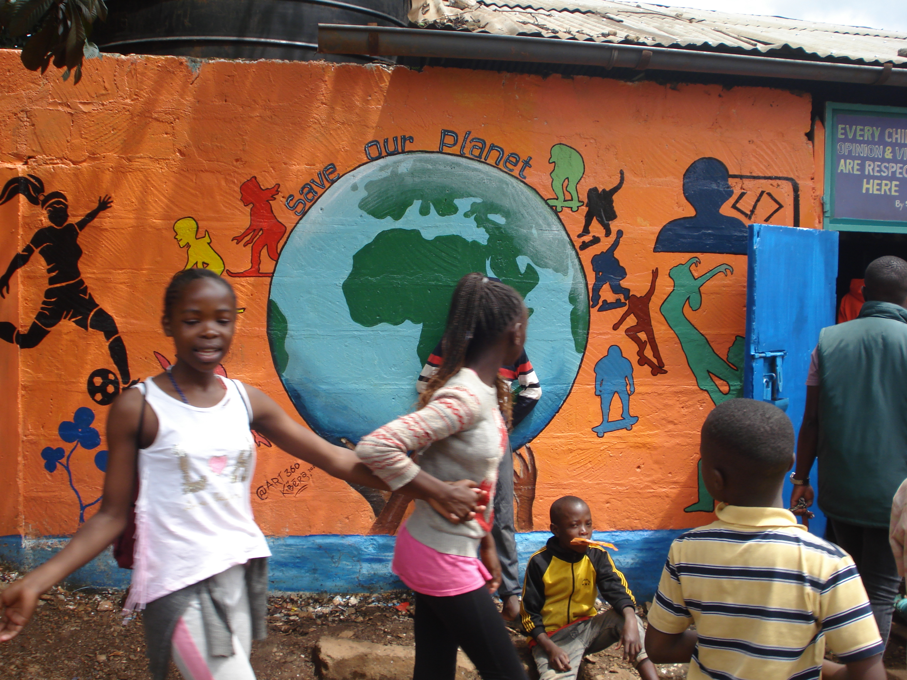 Painting of Planet Earth on the wall of
                          Project Elimu centre in Kibra, Nairobi. Caption above the mural is Save Our Planet. Children are
                          playing in front of the mural.