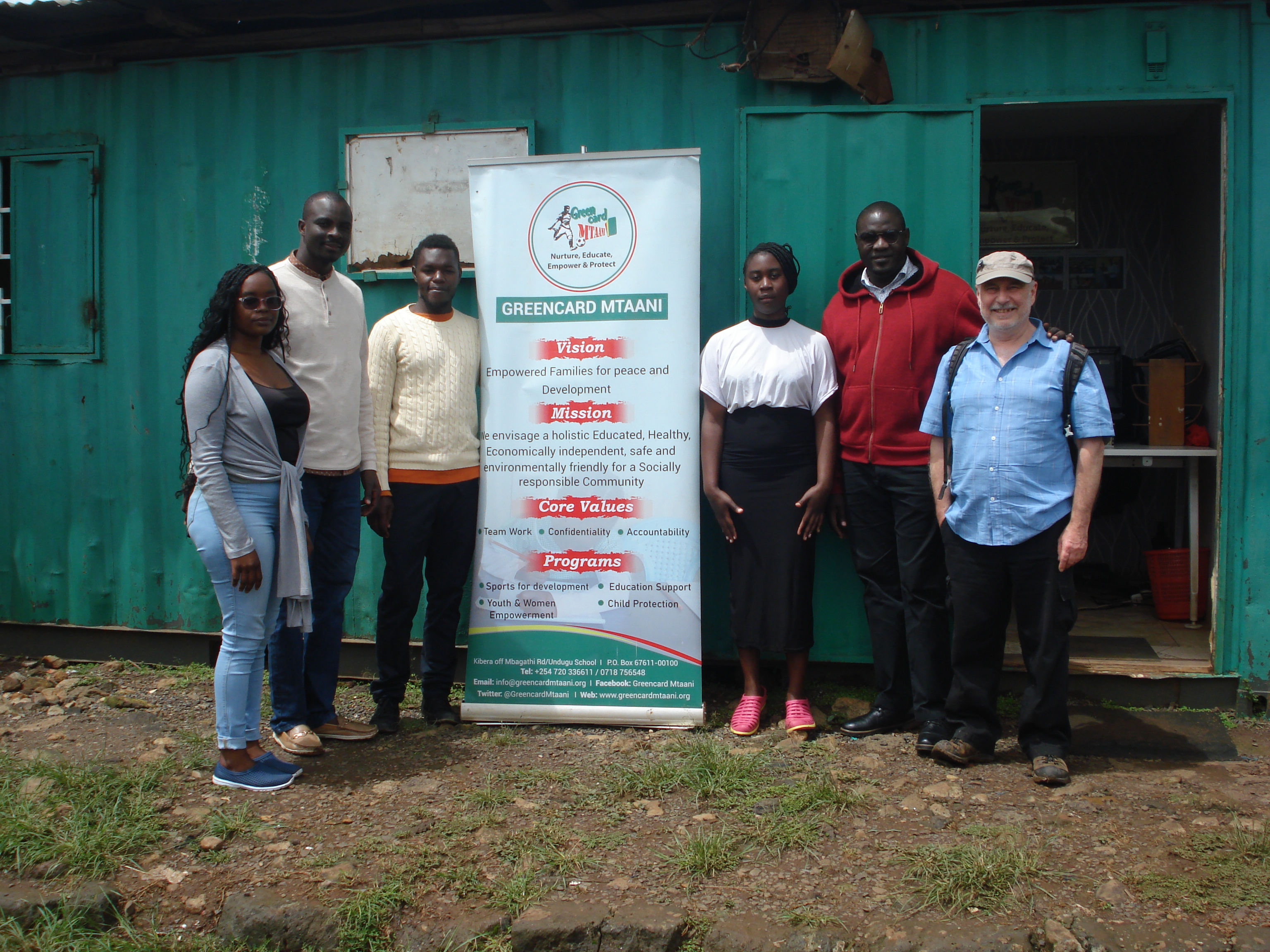 Greenfield Mtaani NGO staff standing outside office in Kibra district, Nairobi.F